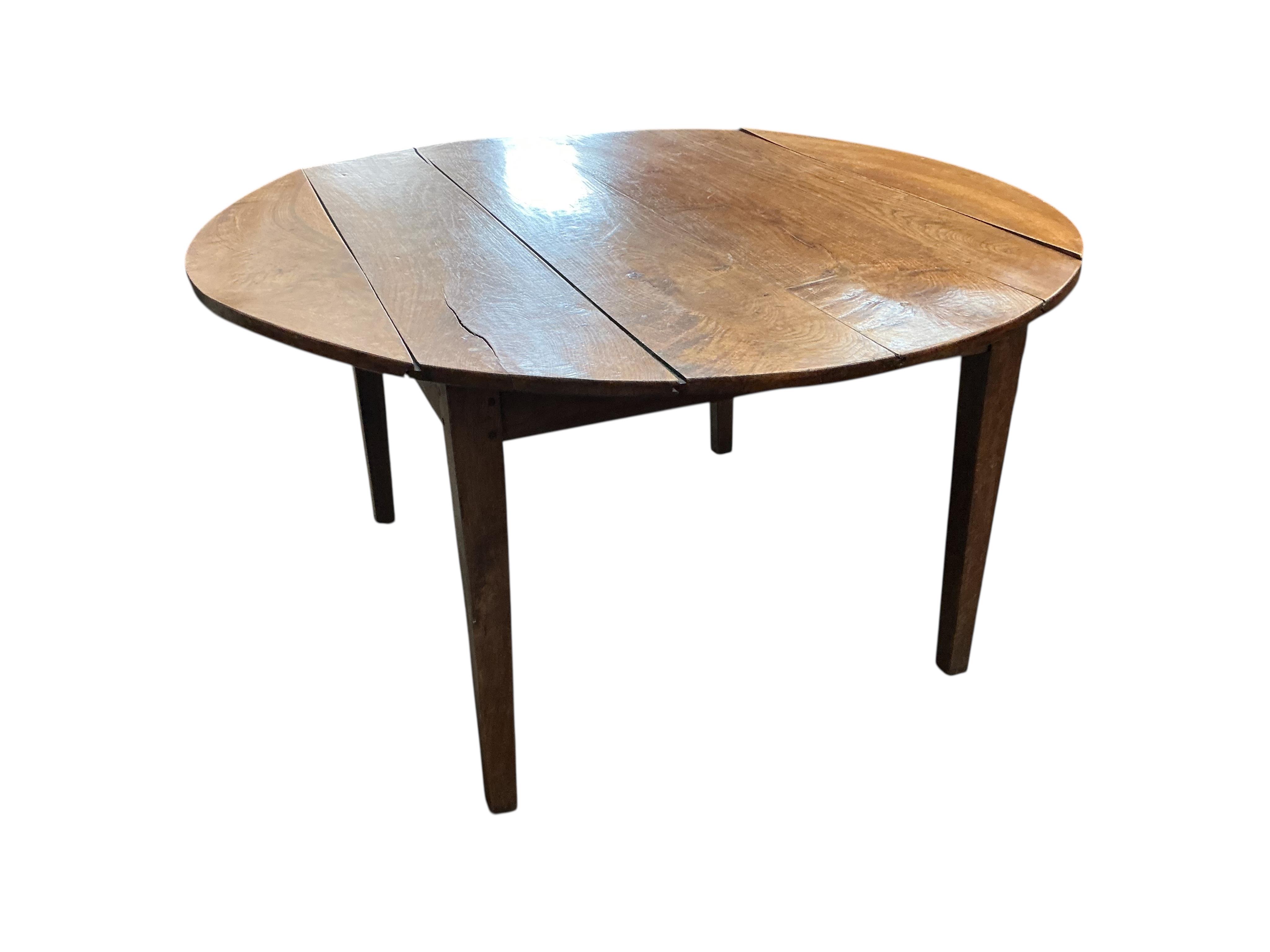 A 19th century French Provincial oak drop leaf dining table, diameter 138cm, extended, height 73cm